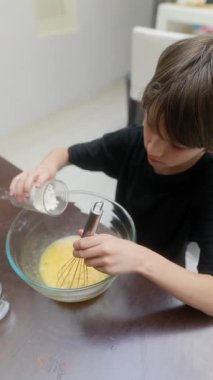 Genç, hevesli bir çocuk, yumurta çırpmayı ve çeşitli rengarenk malzemelerle yemek yapmayı zevkle öğrenir.