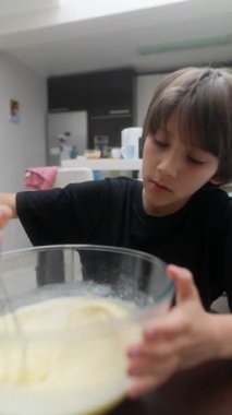 Genç bir çocuk hamuru bir kasede karıştırmaya, yaratıcılığını ve neşesini çok güzel bir şekilde göstermeye odaklanır.