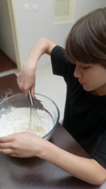 Bir çocuk zevkle bir kasede lezzetli hamuru karıştırır, eğlenceli ve eğlenceli bir pişirme deneyimi sunar.