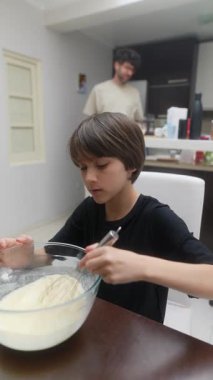 Modern bir mutfak ortamında, genç bir çocuk ustalıkla bir yemek tarifi için lezzetli bir karışım hazırlar.