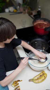 Genç bir çocuk neşeyle taze muzla krep pişirir, yaratıcılık ve eğlence gösterisi yapar.