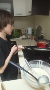 Genç bir çocuk ustalıkla krep pişiriyor ve mutfakta çeşitli lezzetli yemekler hazırlıyor.