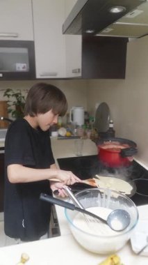 Çağdaş bir mutfak ortamında, yetenekli genç bir şef ustalıkla lezzetli krepler yapıyor.