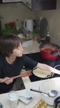 Genç bir çocuk canlı, çağdaş bir mutfak içinde yemek pişirmekten, yaratıcılık ve mutfak eğlencesi göstermekten zevk alır.