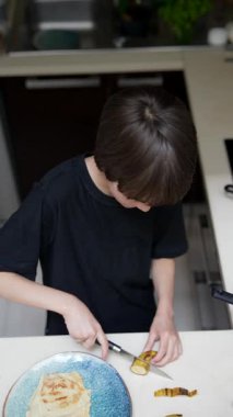 Modern bir mutfakta, genç bir çocuk canlı meyveleri ustalıkla dilimleyip etkileyici bir mutfak yaratıcılığı sergiliyor.