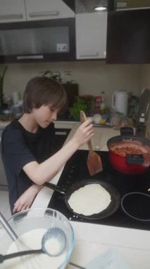 Modern bir mutfakta, bir çocuk ustalıkla krep yapar, aşçılık yaratıcılığını ve aşçılık sevgisini gösterir.