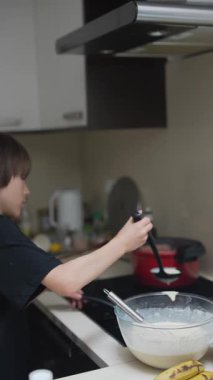 Modern bir mutfakta, genç bir çocuk leziz krepler pişirir, aşçılık hevesini gösterir.