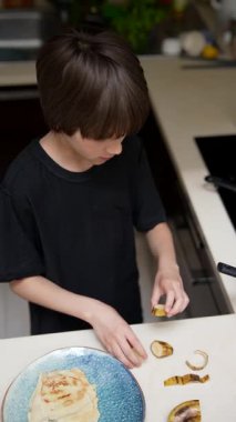 Genç bir çocuk, neşeli bir mutfak ortamında muzlarla yaratıcı yemek pişirme faaliyetlerine girişir.