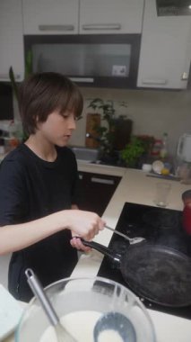 Genç bir çocuk, modern bir mutfakta tutkusunu ve yaratıcılığını sergileyerek çeşitli heyecan verici yemek pişirme faaliyetlerine girişir.