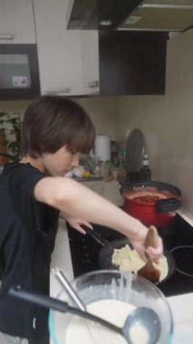 Neşeli bir mutfak ortamında, bir çocuk sevinçle bir aile üyesinin yanında lezzetli krepler pişirmeyi öğrenir.