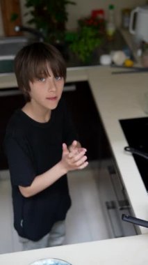 Küçük bir çocuk neşeyle yemek pişiriyor, dikkatlice muz kesiyor ve mutfakta lezzetli krepler hazırlıyor.