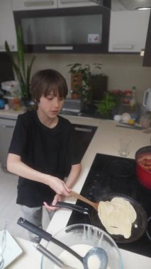 Genç bir insan, aşçılık yeteneğini ve tutkusunu sergileyerek, modern bir mutfakta ustalıkla krep hazırlar.