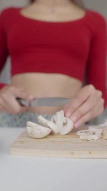 Bir insan ahşap kesim tahtasıyla taze mantarları ustalıkla dilimleyip mutfak tekniklerini sergiliyor..