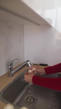 Bir insan taze ve sağlıklı ürünleri çağdaş bir mutfak lavabosunda akarsu altında tamamen yıkıyor.