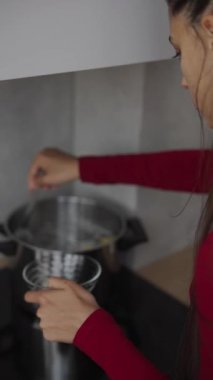 Modern bir mutfakta tencereyi karıştıran, yemek pişirme sürecinin tadını çıkaran ve mutfak yeteneklerini sergileyen biri.