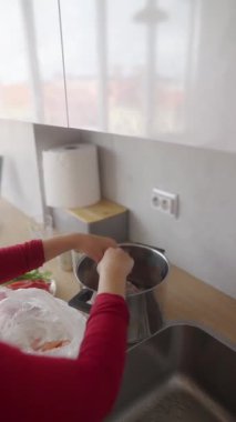 Bir kadın, taze malzemeler ve modern yemek takımları kullanarak parlak bir mutfakta ustalıkla lezzetli yemekler hazırlıyor.