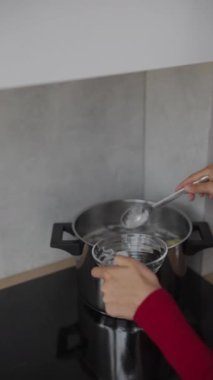 Yetenekli bir kadın, yemek pişirme tekniklerini sergilemek için kaşıkla tenceredeki malzemeleri ustalıkla harmanlıyor.