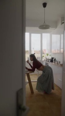 Huzurlu ve huzurlu bir mutfak sahnesinde özenle dizüstü bilgisayarları üzerinde çalışan odaklanmış bir kişi sergileniyor.