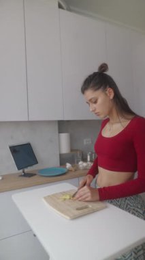 Genç bir kadın şık, modern bir mutfakta lezzetli yemekler hazırlarken yemek pişirme becerilerine odaklanıyor.