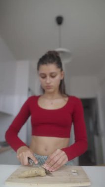 Genç bir kadın modern bir mutfakta taze zencefili ustalıkla hazırlıyor. Yemek pişirme uzmanlığını ve yaratıcılığını sergiliyor.