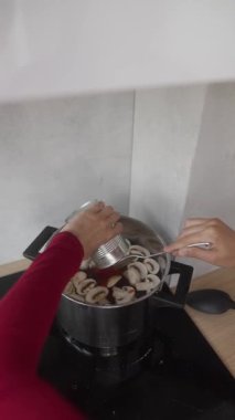 Bir insan fırında pişirirken taze mantarlara ustalıkla lezzetli bir sos ekler.