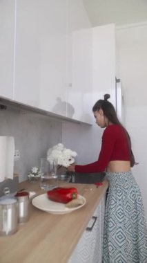 Harika becerileri olan şık bir kadın, modern mutfak alanında taze çiçekleri çok güzel düzenler.