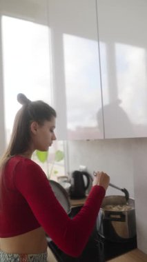Parlak ve modern bir mutfakta, genç bir kadın özenle ve ustalıkla lezzetli bir yemek hazırlar.