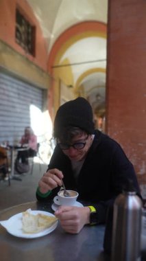 Rahatlamış bir birey, güzel bir açık hava ortamında lezzetli bir fincan kahvenin ve enfes bir pastanın tadını çıkarıyor.