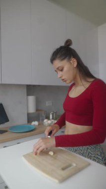 Güzel tasarlanmış, modern bir mutfakta, genç bir kadın besleyici yemek hazırlamak için mutfak becerilerini kullanır.