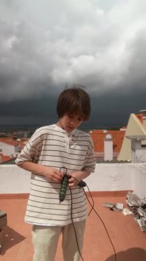 Genç bir insan dikkatle çatıdaki karmaşık bir elektronik cihaza odaklanıyor. Arkasında büyüleyici bir gökyüzü var.