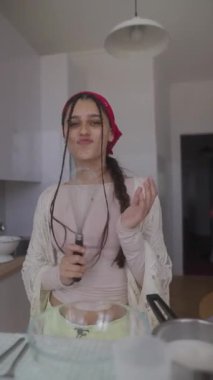 Genç bir kadın, neşe ve yaratıcılığını yemek pişirerek ifade eder. Parlak, modern mutfağında çırpıcıyı ustalıkla kullanır.