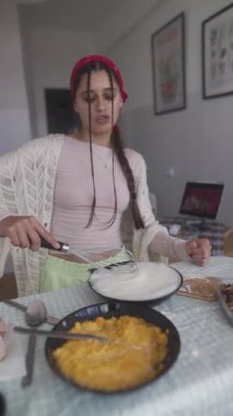 Neşeli genç bir kadın, şık bir mutfakta zevkle tatlı hazırlıyor ve mutfak yeteneklerini sergiliyor.