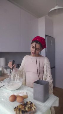 Sıcak ve rahat bir mutfakta bir kadın ustalıkla taze malzemeler pişirirken aynı zamanda yemek pişirmekten zevk alıyor.