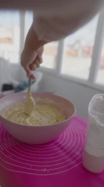 Bir el sıcak, güneşli bir mutfakta pasta hamurunu hararetle karıştırırken büyüleyici bir pastel paspasın üzerinde dinleniyor.