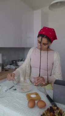 Bir kadın yaratıcı bir yemek oturumu sırasında parlak ve renkli bir mutfakta taze malzemeler hazırlar.