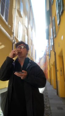 Renkli binalarla dolu bir sokakta sokak yemeklerinin tadını çıkaran genç bir birey..