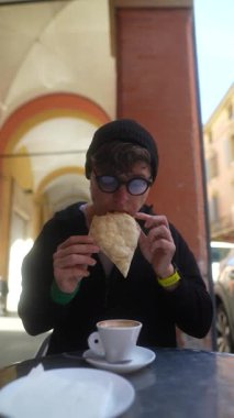 Kafede kahve ve taze ekmekten hoşlanan bir insan, arka planda resimli kemerler olan bir kafede.