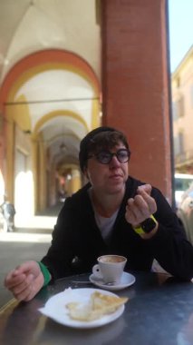 Bir insan, arka planda kemerler olan büyüleyici bir kafede kahve ve pastadan hoşlanır.