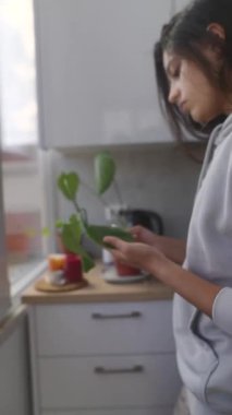 Parlak bir mutfakta güzel bir bitkiyle ilgilenen bir insan, kapalı alanda popüler bahçıvanlık eğilimlerini ön plana çıkarıyor.