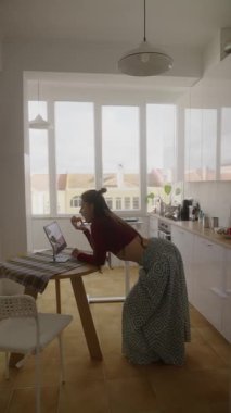 Bir kadın, çağdaş bir cazibe yayan şık ve modern bir mutfağa yerleştirilmiş dizüstü bilgisayarıyla derinden ilgilenir.