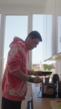 Genç bir adam parlak bir mutfakta lezzetli yemekler hazırlıyor. Mutfak yeteneklerini ve yaşam tarzını gösteriyor.