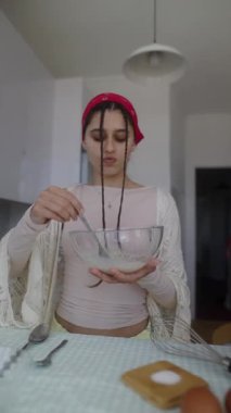 Genç bir kadın sıcak bir mutfakta neşe içinde yemek pişiriyor, canlı bir kase taze malzemeyle yeteneklerini sergiliyor.