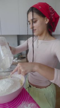 Ustalıkla ve ustalıkla unu bir kâseye karıştıran genç bir kadın, pişirmenin saf keyfini güzel bir şekilde yakalıyor.