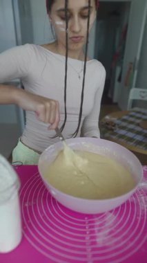 Genç bir birey, modaya uygun, renkli bir mutfakta leziz bir hamuru canlandırıyor.