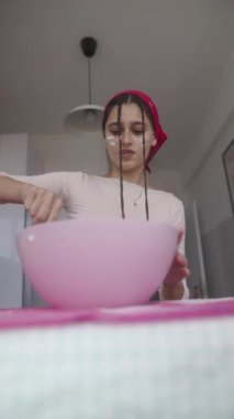 Renkli bir mutfakta, genç bir kadın pişirmek, yaratıcılığını göstermek için taze malzemeleri ustalıkla karıştırır.