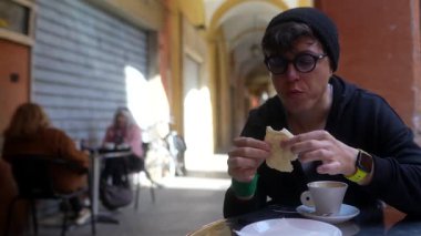 Açık hava kafede kahve ve ekmeğin tadını çıkaran biri.