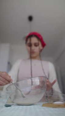 Genç bir insan düzenli olarak sıcak ve sıcak bir mutfakta cam bir kasenin içinde çeşitli pişirme malzemeleri hazırlıyor.