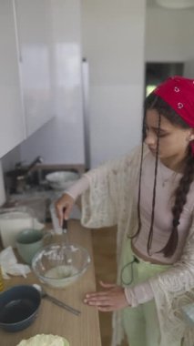 Genç bir kadın modern bir mutfakta yemek hazırlıyor, geleneği çağdaş mutfak becerileriyle harmanlıyor.