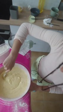 Canlı ve renkli bir mutfakta, bir insan neşeyle pürüzsüz bir hamuru karıştırır, pişirmenin keyfini tamamen kucaklar.