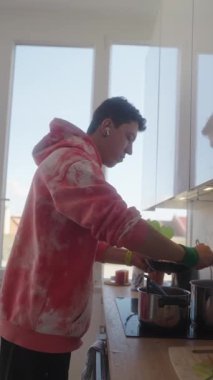 Genç bir aşçı şık bir mutfakta taze ve kaliteli malzemeler kullanarak lezzetli bir yemek hazırlıyor.